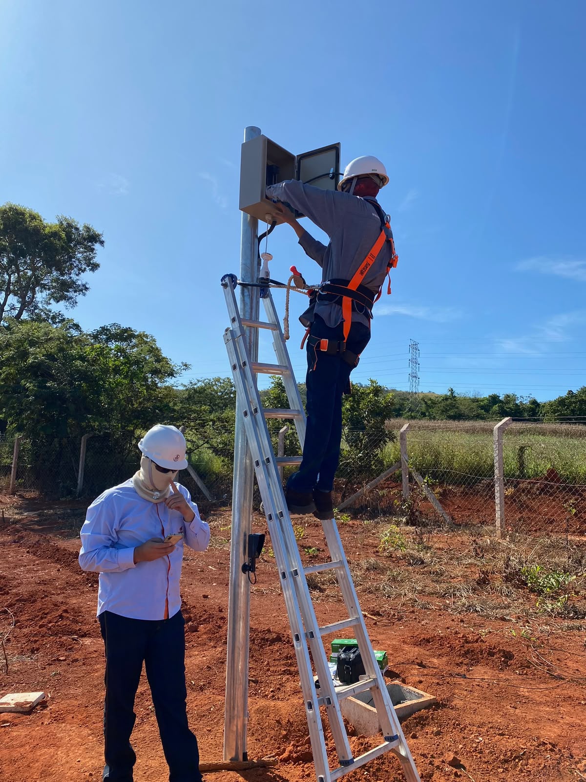 Técnico instalando equipamento de monitoramento em poste na zona rural