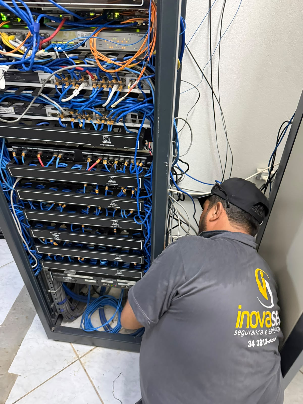 Técnico InovaSeg organizando cabeamento de rack de rede